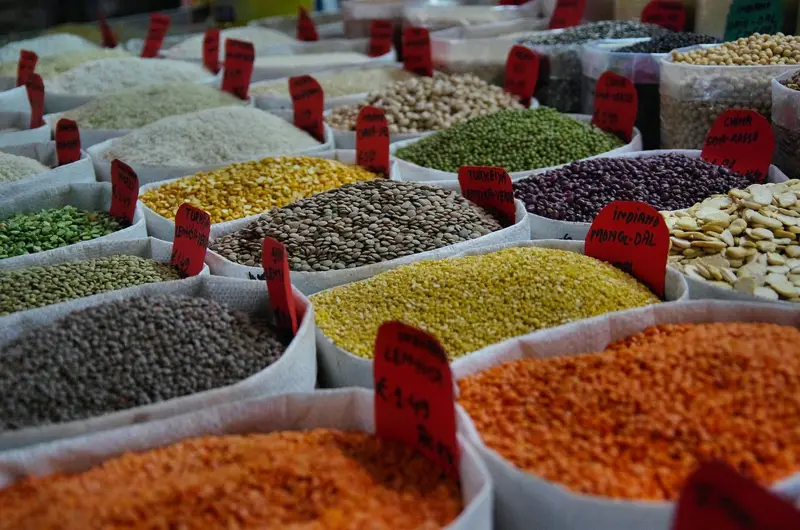 Open sacks of red lentils, chickpeas and rice with price cards at a bazaar
